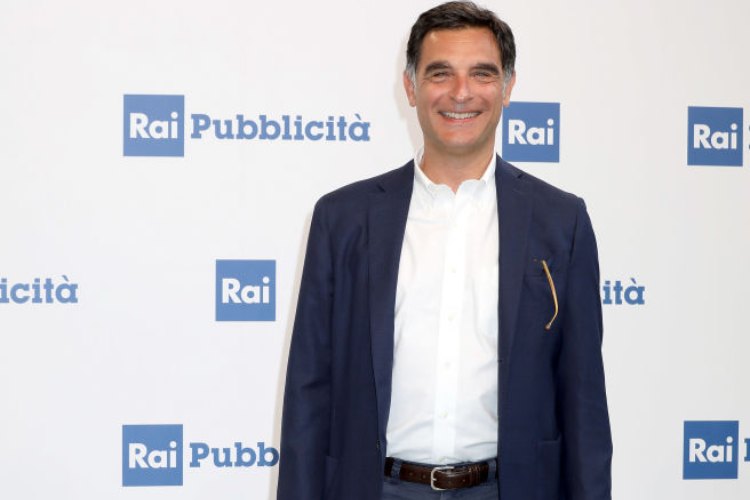 Tiberio Timperi in posa davanti ai cartelloni pubblicitari della Rai